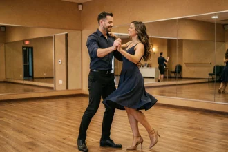 Homme charismatique guidant une partenaire en danse zouk dans un studio de danse aux reflets chaleureux